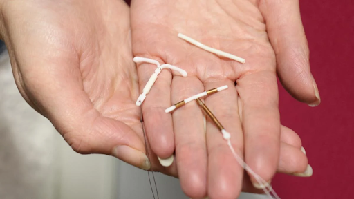 Mão segurando DIU hormonal, DIU de cobre e implante subdérmico